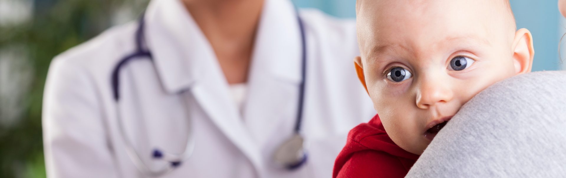 Baby auf dem Arm der Mutter beim Arzt